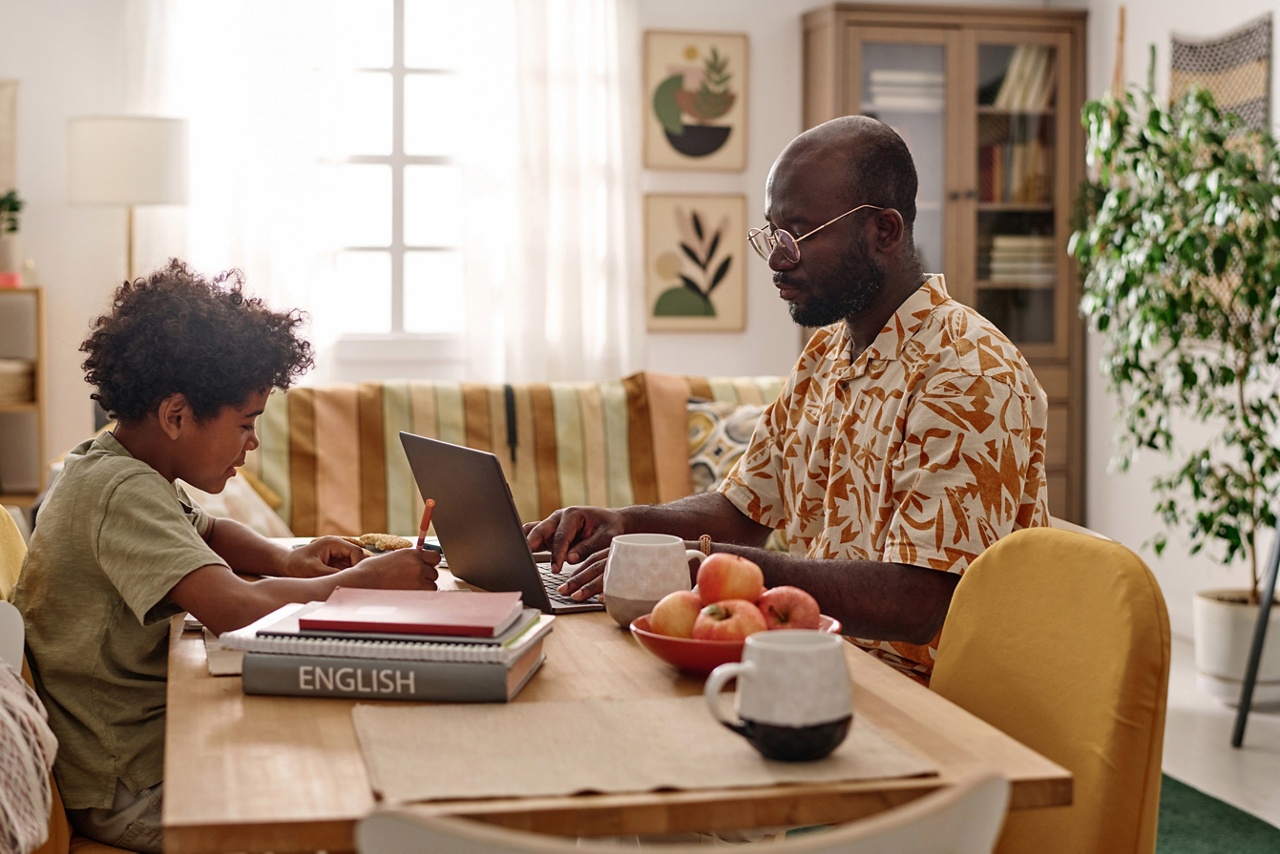 Photo d’un entrepreneur travaillant à l’ordinateur dans sa cuisine avec son enfant représentant la conciliation travail-famille