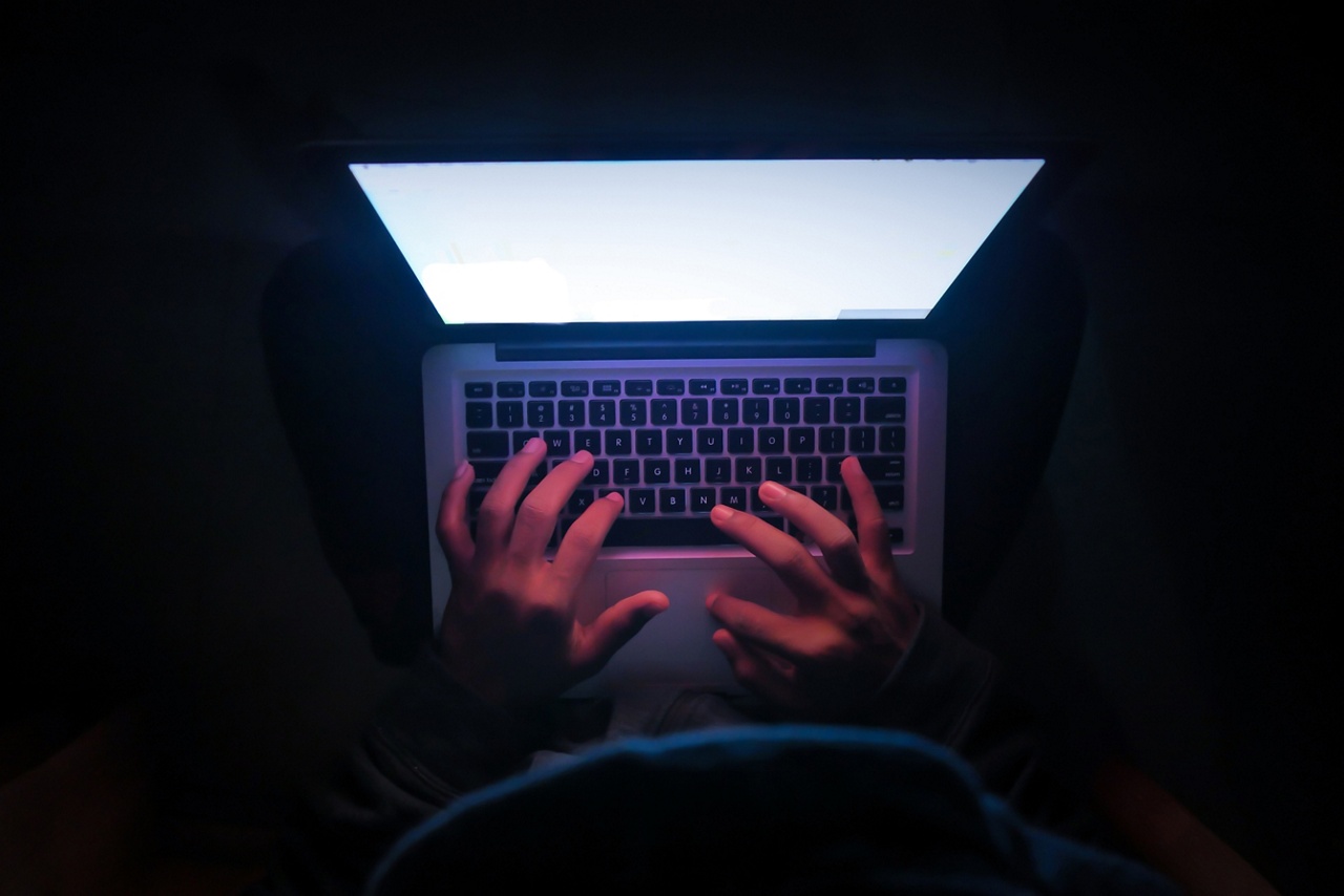 Photo deux mains sur un clavier d’ordinateur portable sur fond noir pour un article sur la fraude par personnification