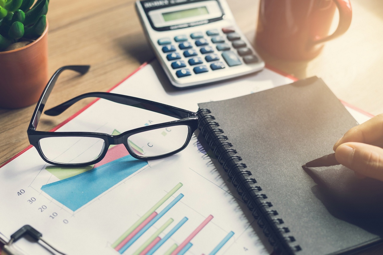 Photo de lunettes et de calculatrice sur un bureau pour un article sur l’optimisation de la politique de placement pour les OBNL 