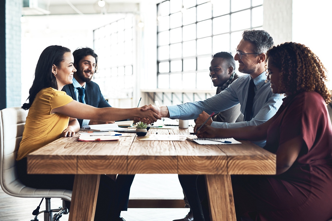 Photo of two groups of people shaking hands representing a management buyout 