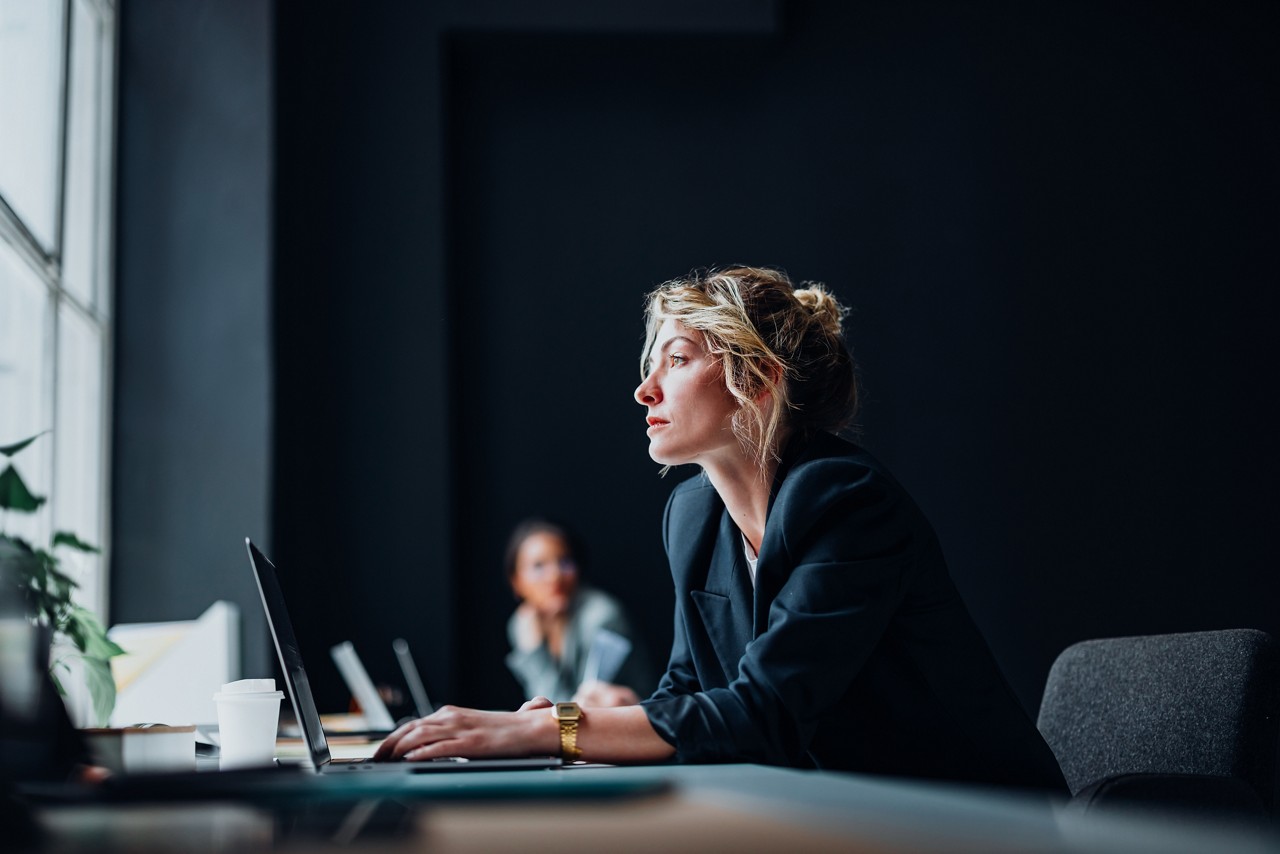 Serious businesswoman sitting at desk and typing something on a laptop computer keyboard.
