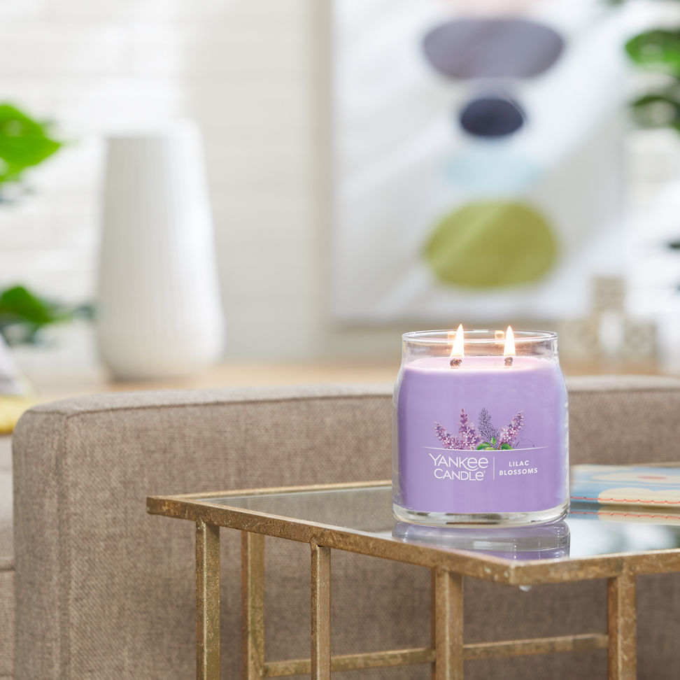 lilac blossoms signature medium jar candle lit on side table