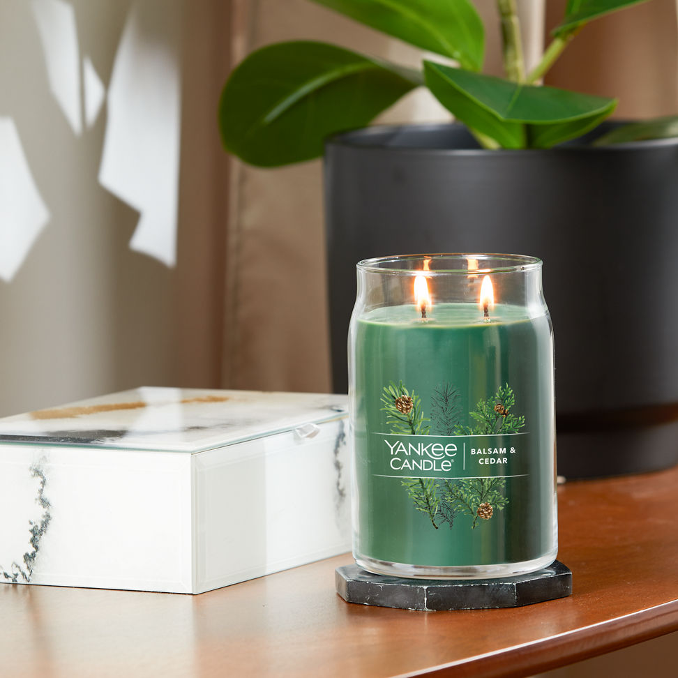 balsam and cedar signature large jar candle lit on side table