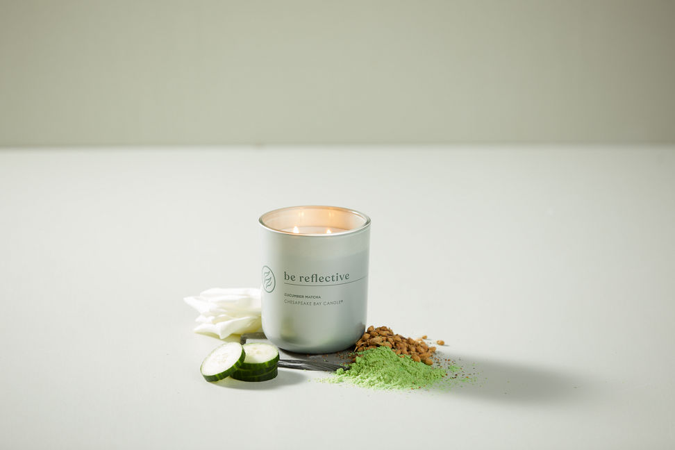 chesapeake bay candle intentions collection be reflective cucumber matcha medium two wick jar candle surrounded by cucumbers, white petals, nuts, and matcha