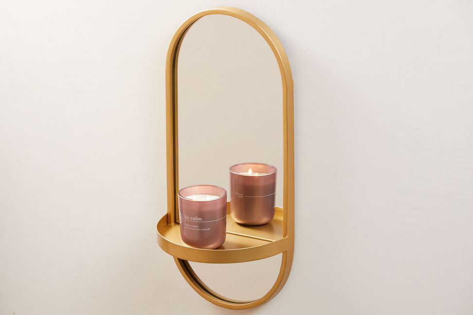 chesapeake bay candle intentions collection be calm coconut santal medium two wick jar candle on a gold mirror hanging on a wall