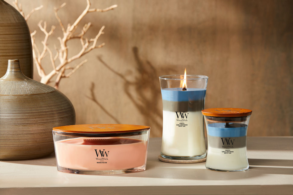 three woodwick candles with brown vases and branches