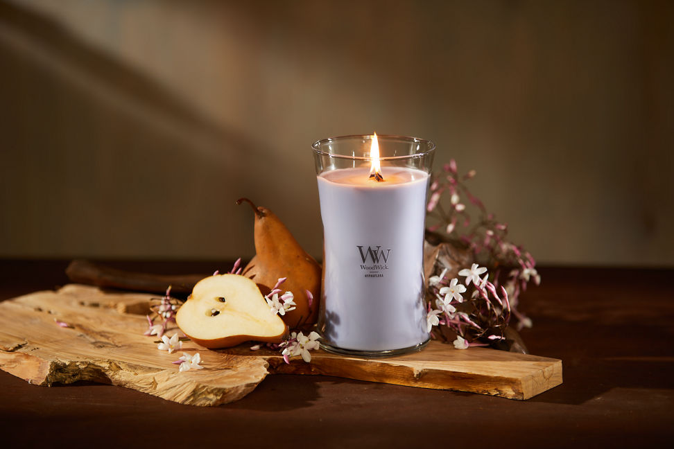 WoodWick Enchanted Destinations Collection Hypnoflora Large Hourglass Candle next to pears and white flowers on a table