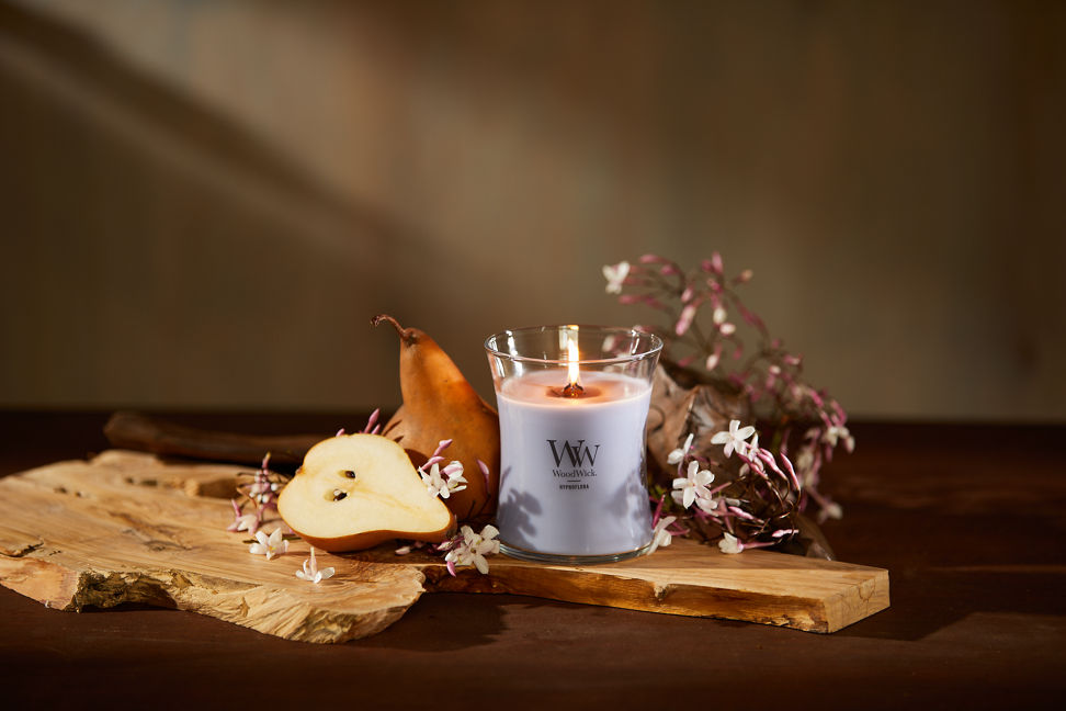 WoodWick Enchanted Destinations Collection Hypnoflora Medium Hourglass Candle next to a pear on a table