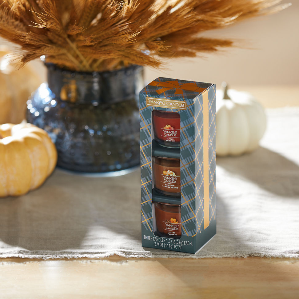 Pumpkin Season Minis Gift Set featuring an Apple Pumpkin Yankee Candle Mini, a Pumpkin Banana Scone Yankee Candle Mini, and a Spiced Pumpkin Yankee Candle Mini on a table with decorative pumpkins and a vase with decorative floral pieces