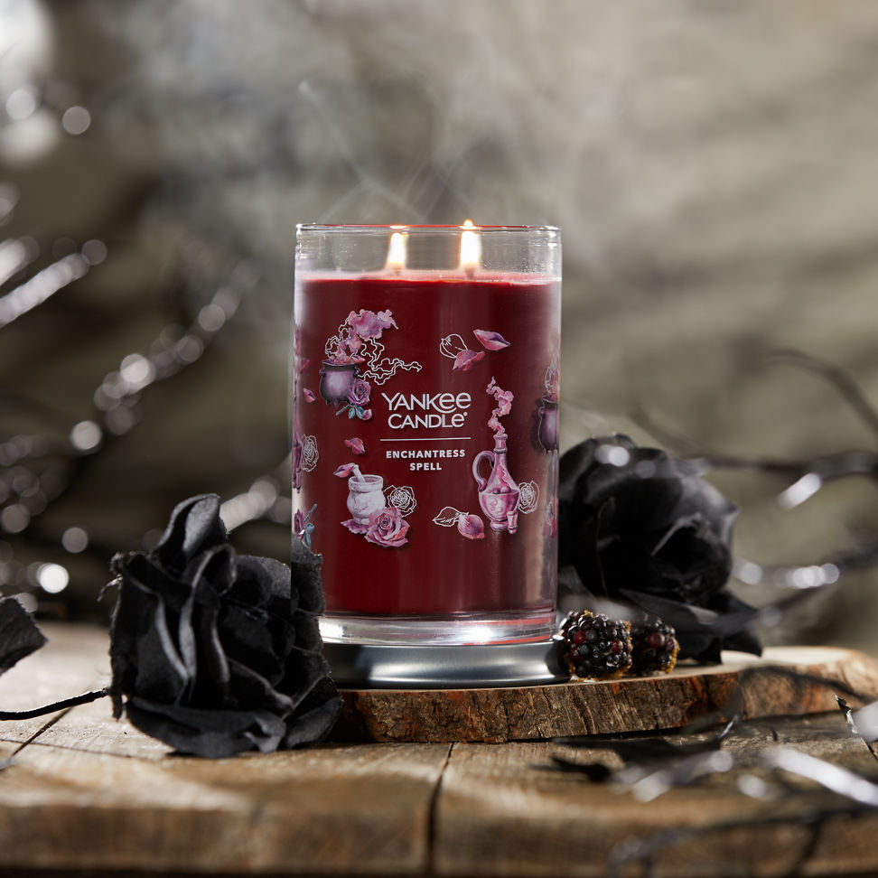 Enchantress Spell Signature Large Tumbler Candle with two black roses on a piece of wood