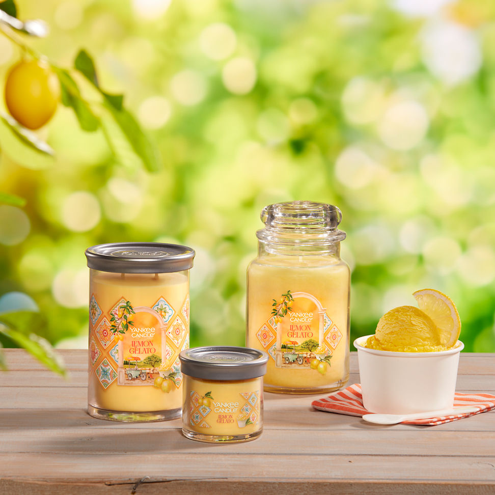 Hello, Italy! Collection Lemon Gelato Signature Large Tumbler Candle, Lemon Gelato Signature Small Tumbler Candle, and Lemon Gelato Original Large Jar Candle on a table with a cup of ice cream and a spoon