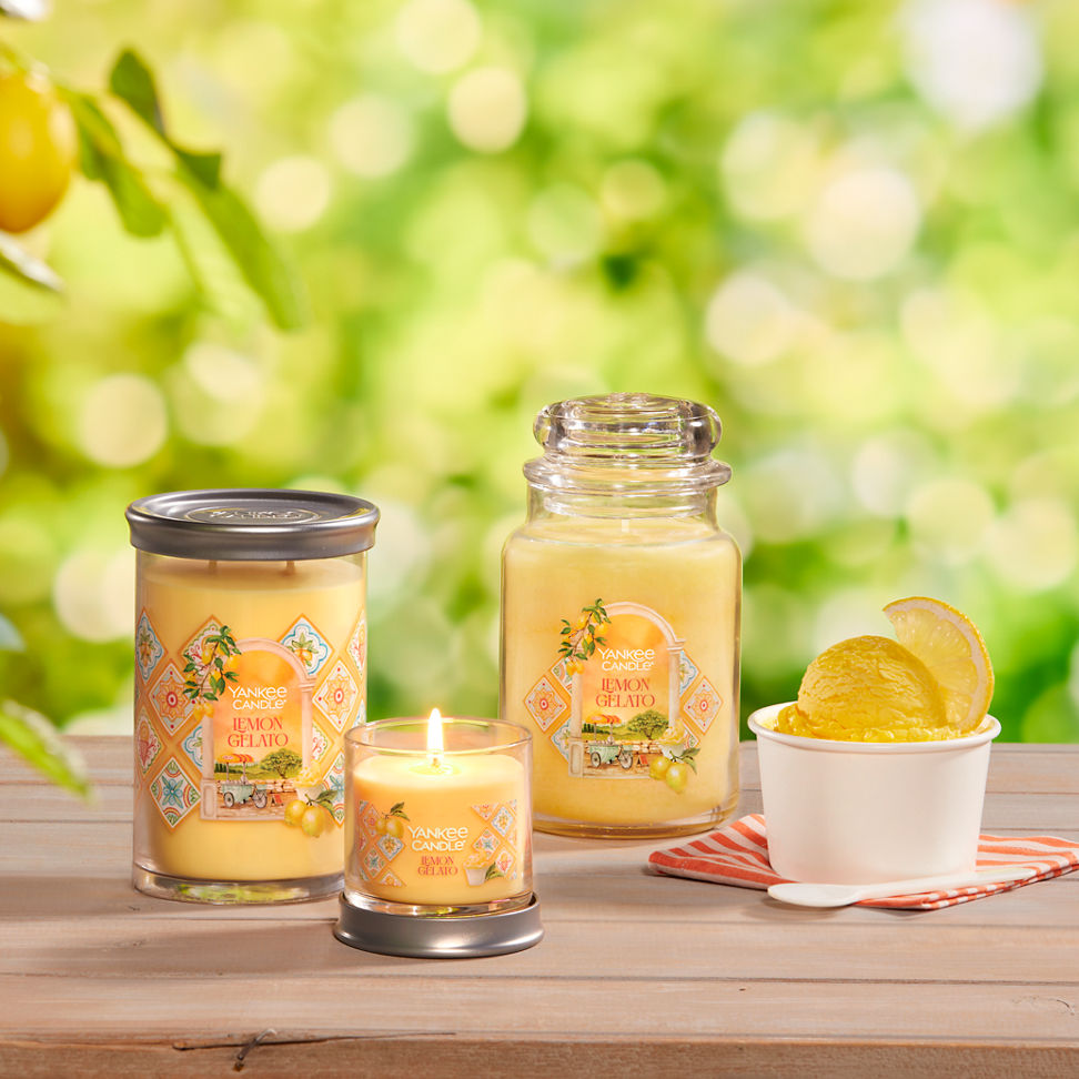 Hello, Italy! Collection Lemon Gelato Signature Large Tumbler Candle, Lemon Gelato Signature Small Tumbler Candle, and a Lemon Gelato Original Large Jar Candle on a table with a cup of ice cream and a spoon