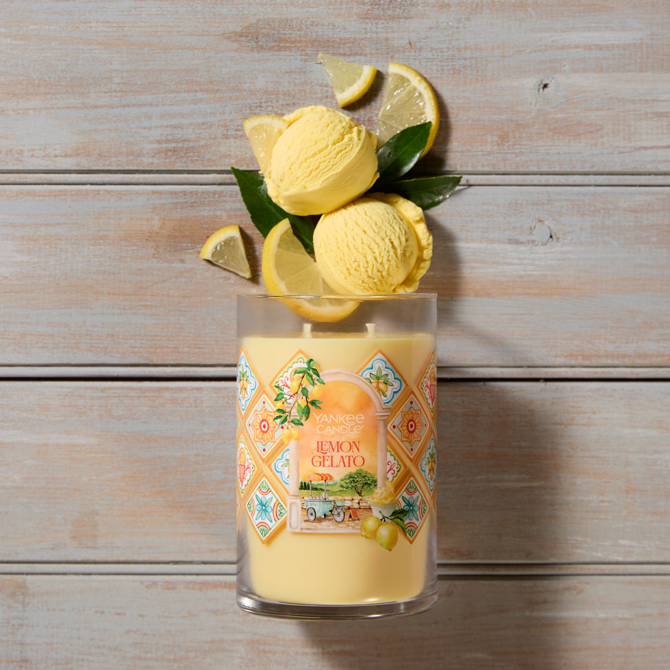 Hello, Italy! Collection Lemon Gelato Signature Large Tumbler Candle laying on a table with scoops of yellow ice cream and lemon slices coming from the top of the candle