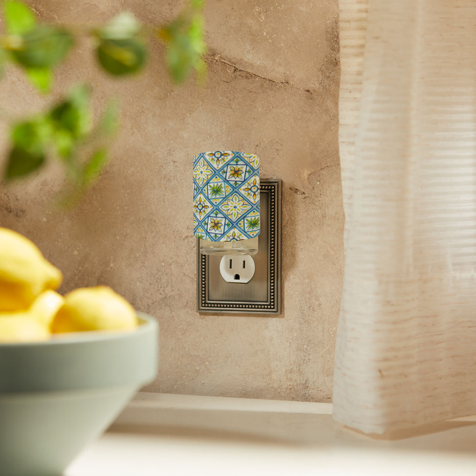 Hello Italy Pattern ScentPlug Diffuser with a light plugged into a wall next to a bowl of lemons