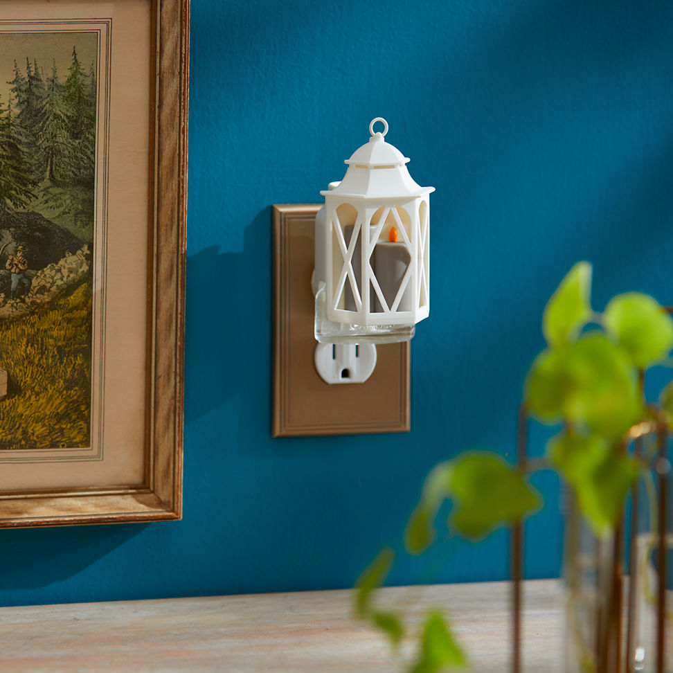 Spring Lantern ScentPlug Diffuser with a light plugged into a wall next to a photo in a frame