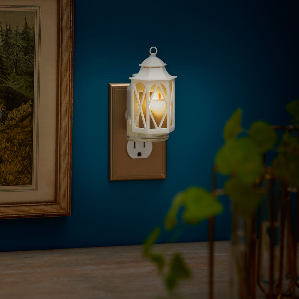 Spring Lantern ScentPlug Diffuser with a light plugged into a wall next to a photo in a frame