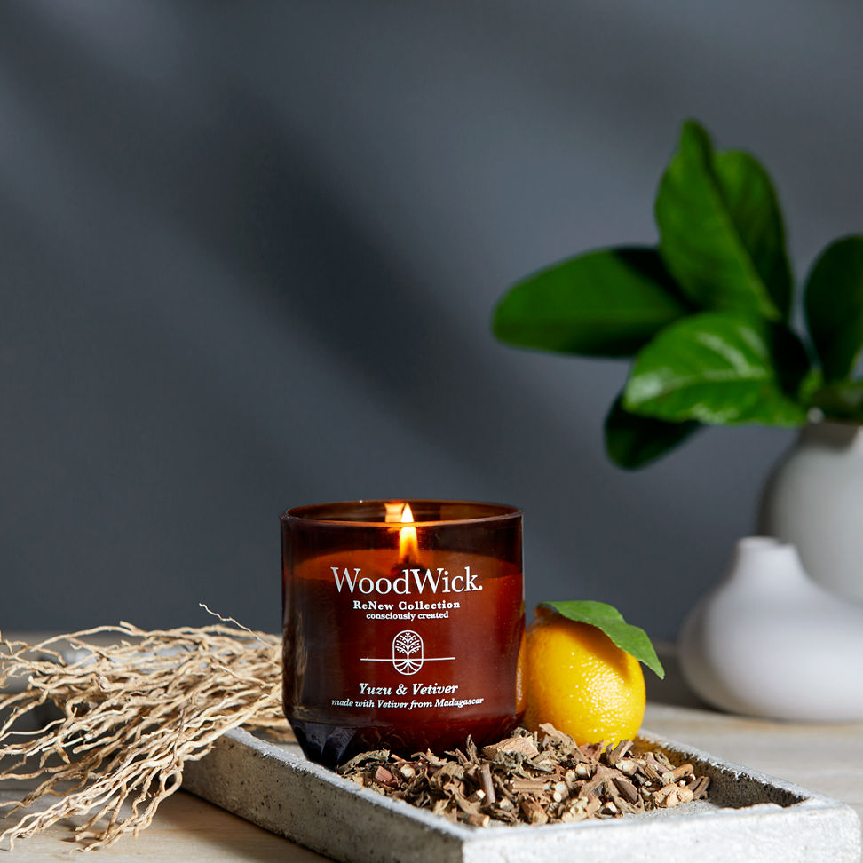 WoodWick ReNew Collection Yuzu & Vetiver Medium Candle next to a lemon on a table