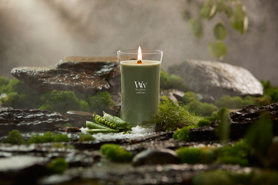 WoodWick Vapour Trails Collection Ethereal Haze Large Hourglass Candle surrounded by rocks, moss, salt, and snap peas