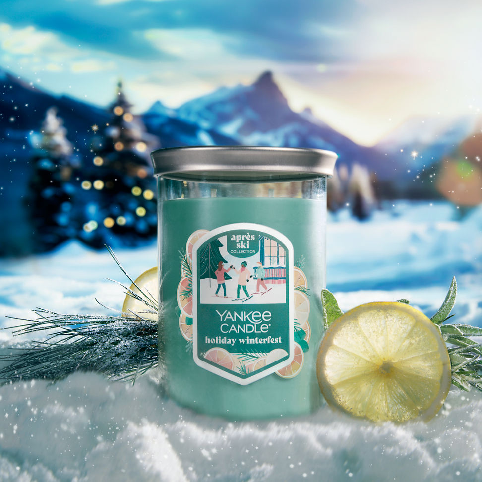 Apres Ski Collection Holiday Winterfest Signature Large Tumbler Candle in snow surrounded by lemon slices, branches, and mountains
