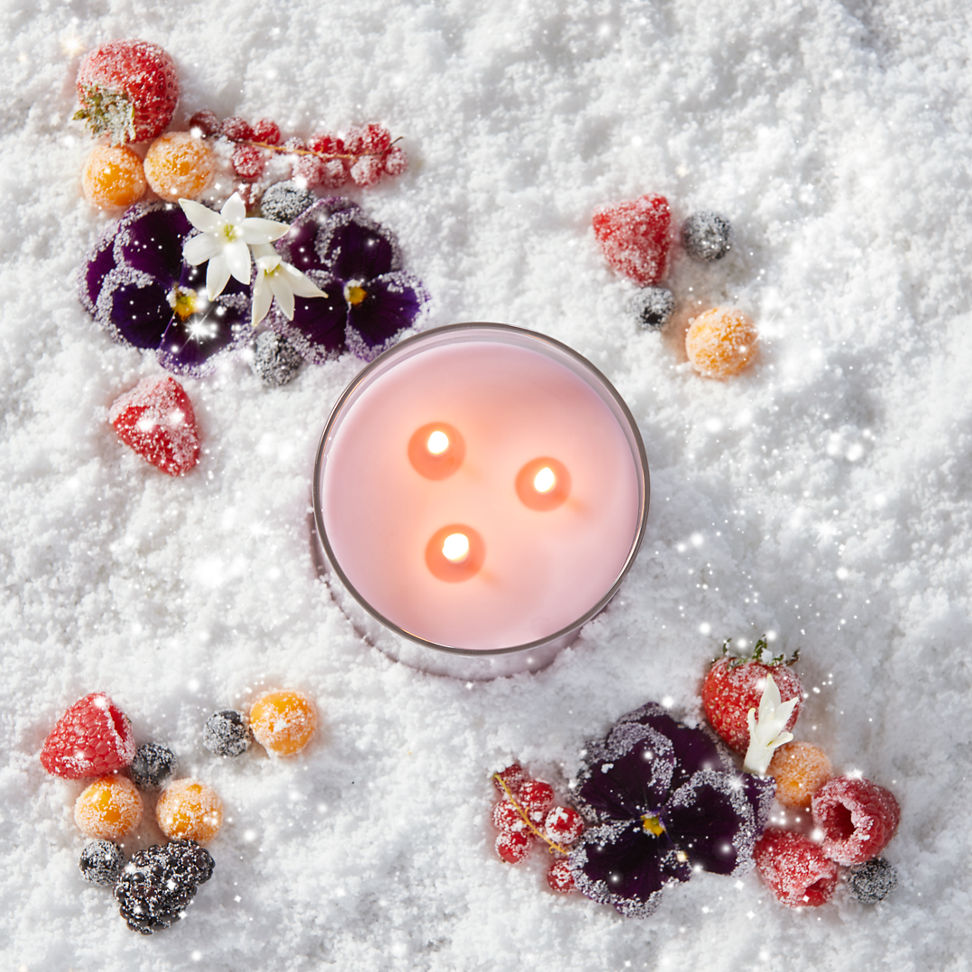 a pink-colored 3-Wick Candle in snow surrounded by berries
