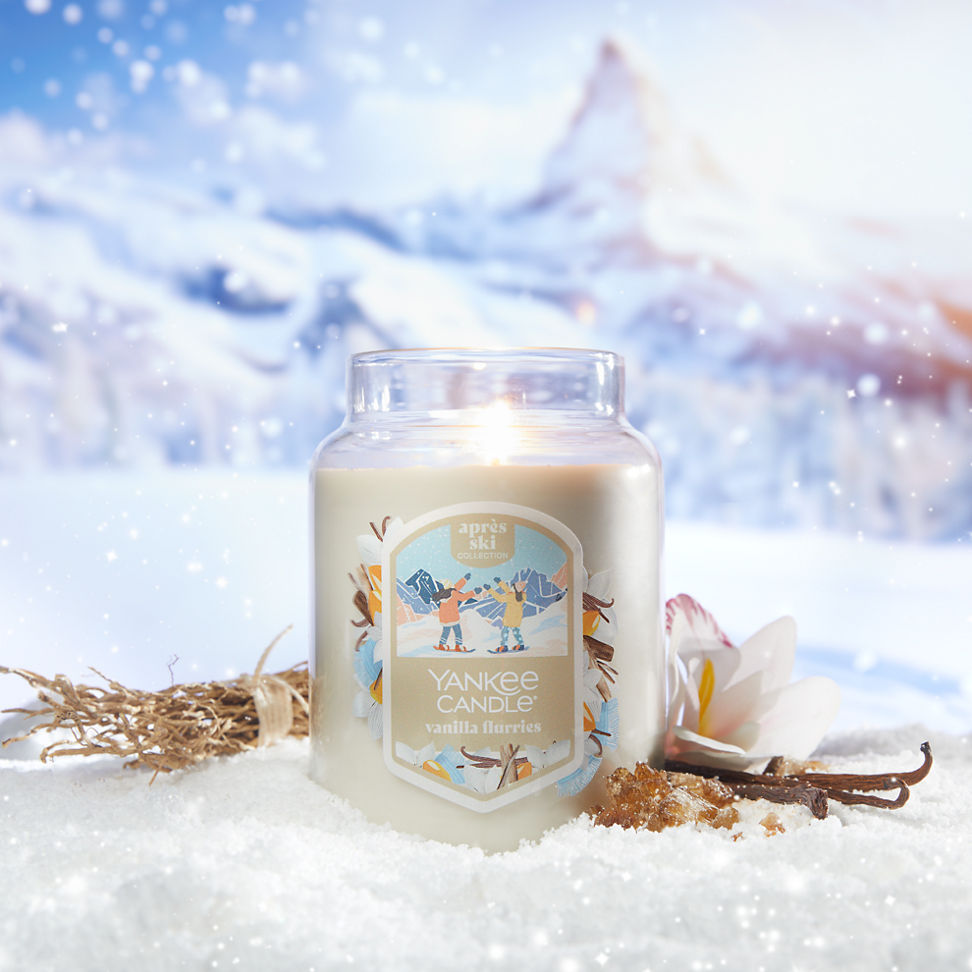 vanilla flurries large jar candle in the snow with vanilla beans, orchids, amber, and dried branches with a mountain scene behind