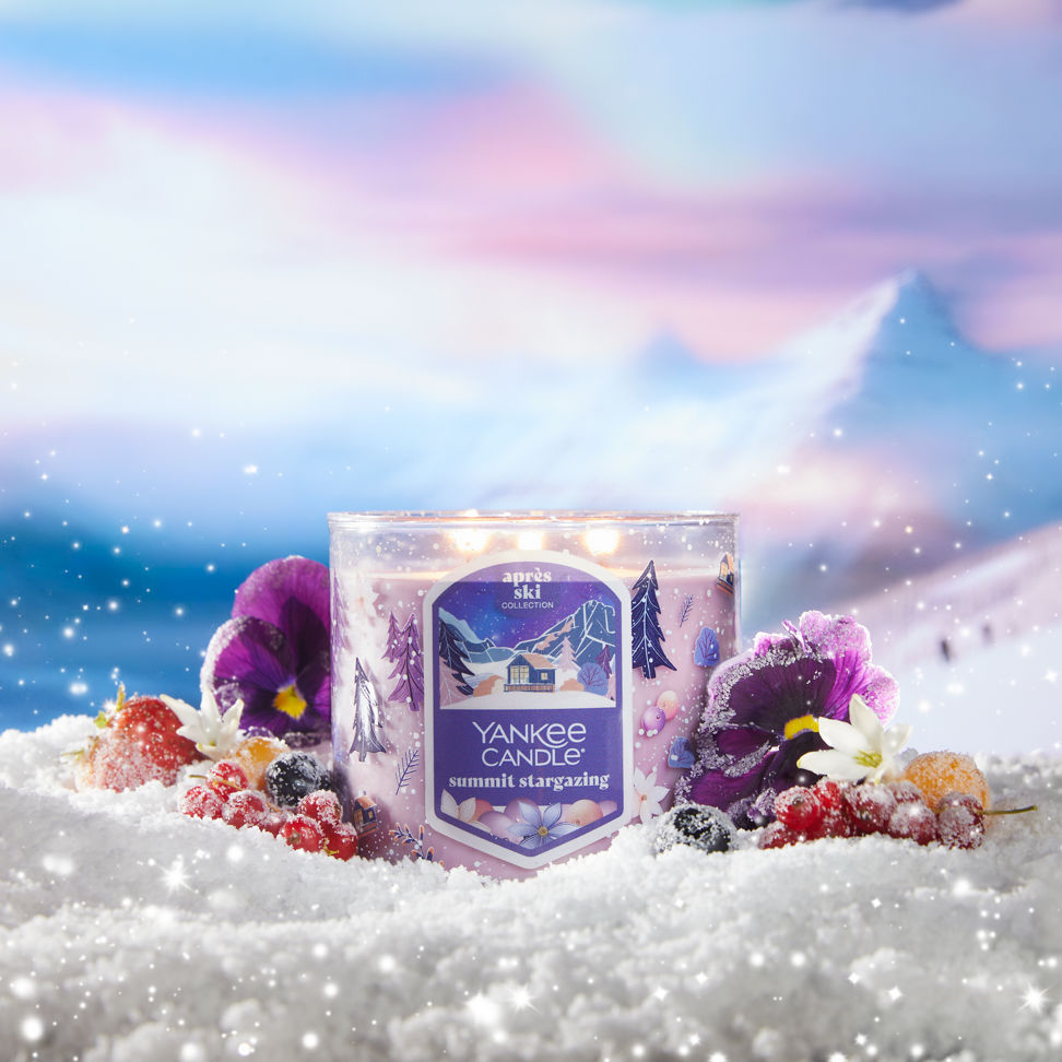 summit stargazing three wick candle on snowy surface with flowers and berries and with mountains in distance
