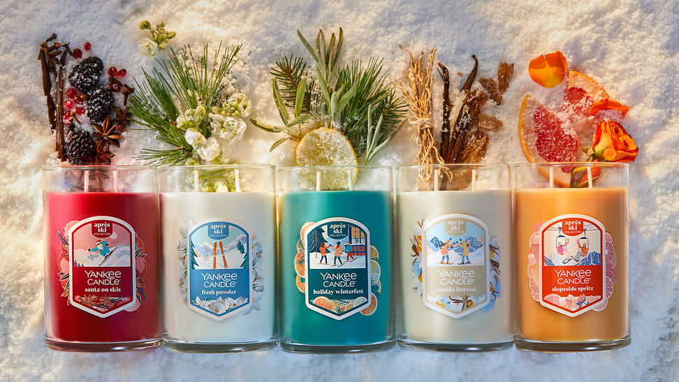 five apres ski tumbler candles with scent ingredients spilling out of the tops on a snowy surface
