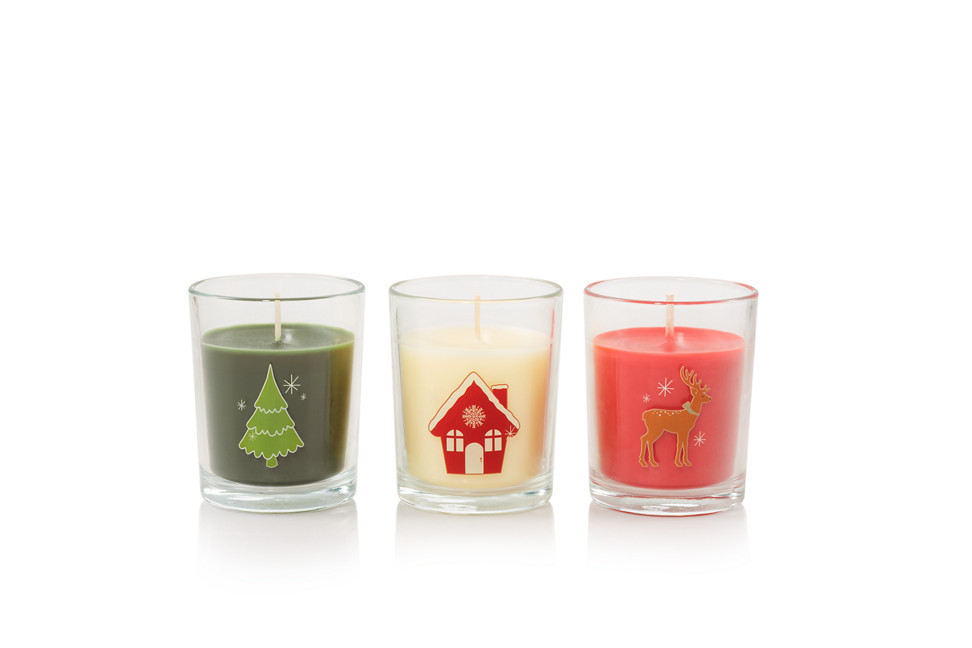Three candles with holiday designs and one each in the fragrances Balsam & Cedar, Christmas Cookie, and Sparkling Cinnamon