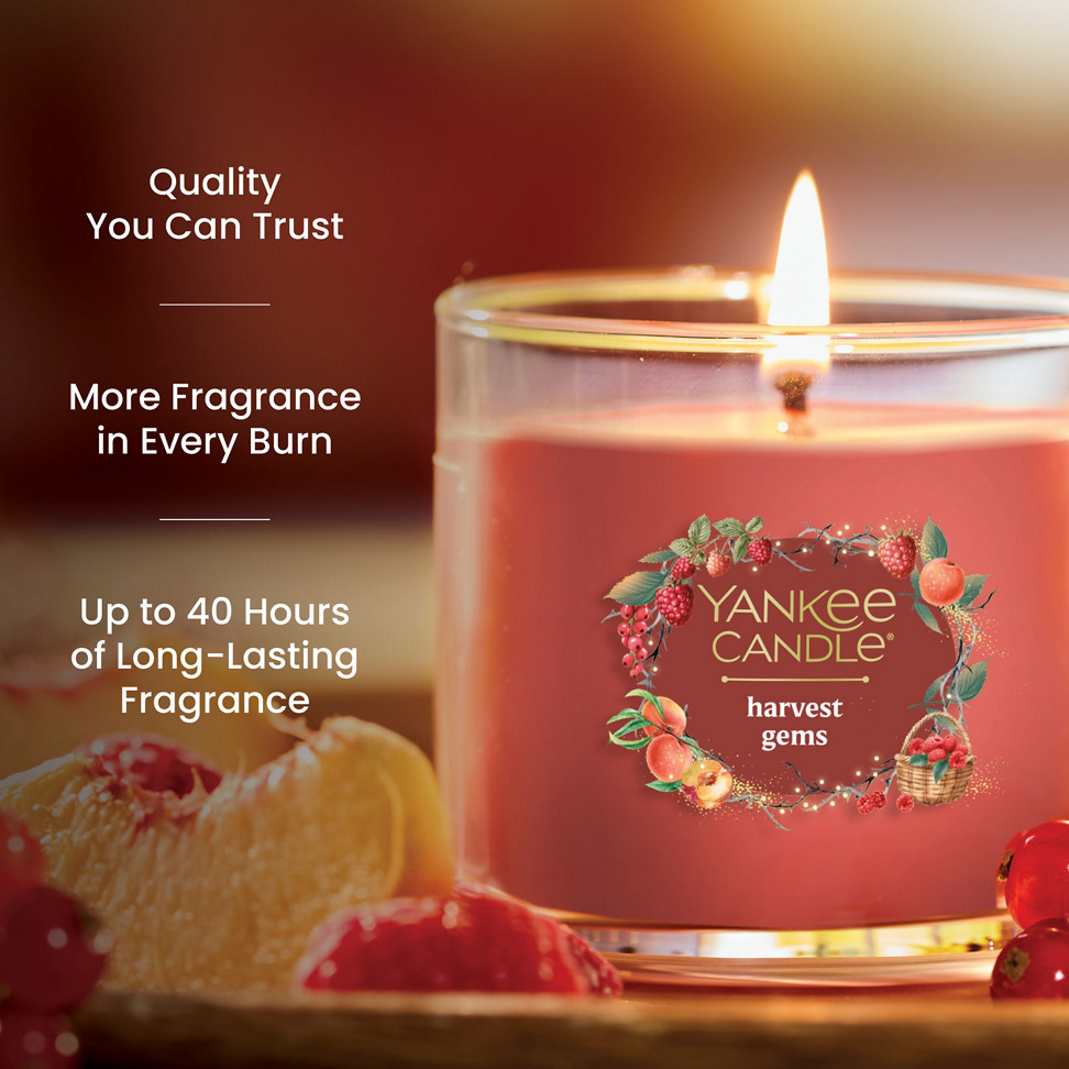 Red glass jar candle with fruit accents, promises up to 40 hours of long-lasting, quality fragrance burn time