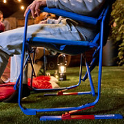 Person relaxing in a blue Coleman Pro Rocker Chair outdoors.