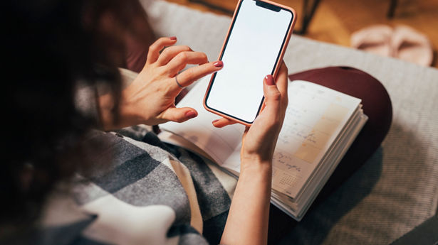 Hands of an unrecognizble woman using a smartphone, a close up.