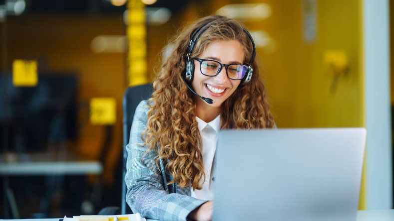 Call center agent with headset working on support hotline in modern office