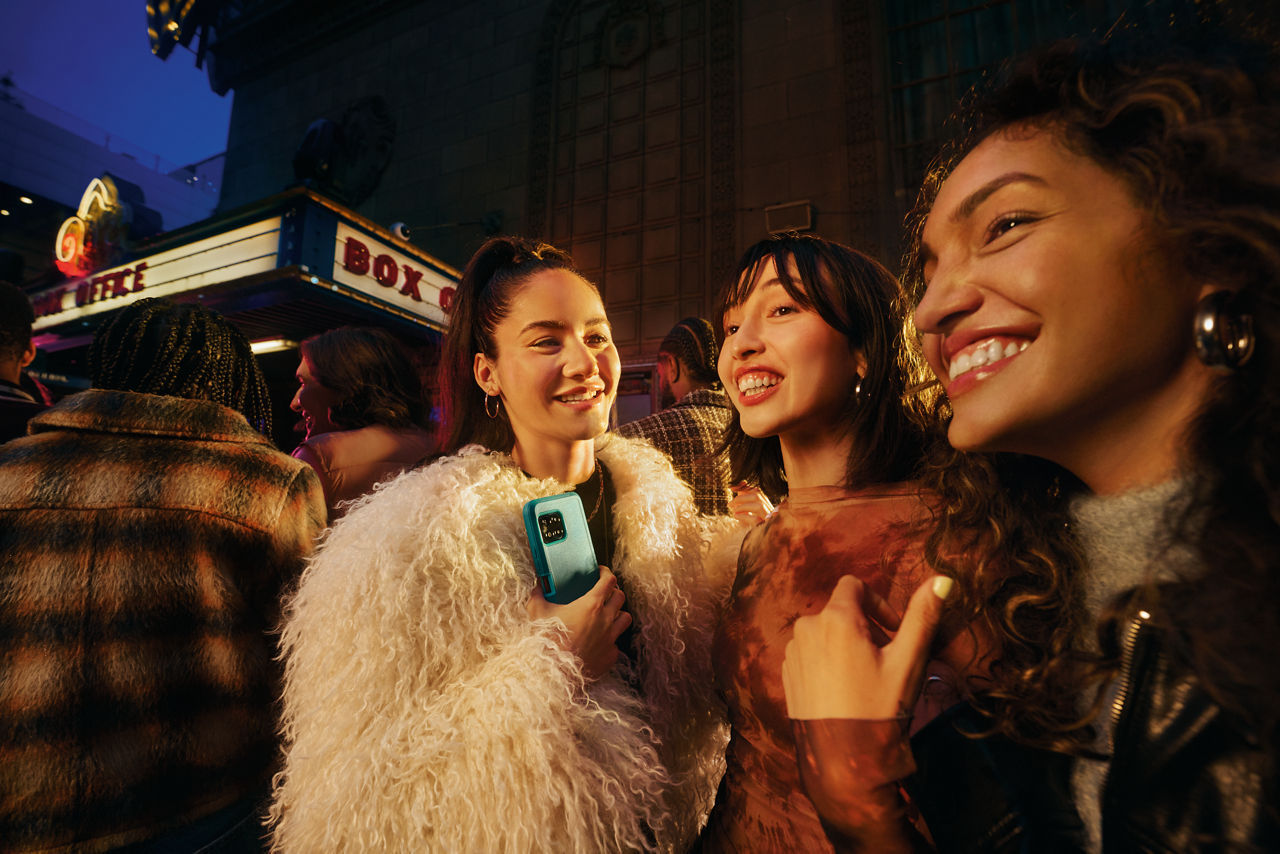 Friends socialize outside venue using smartphone