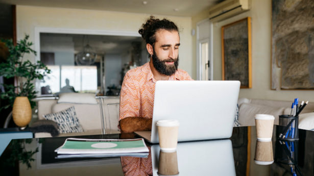 Man working on table at home using laptop shutterstock