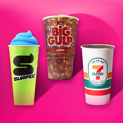 A young woman with braided hair holds a green cup containing a red slush drink. She is wearing a mint green sweater with a cherry embroidery and red sunglasses. The background is plain white, highlighting the vibrant colors and playful mood of the scene.