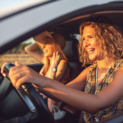 Two women laughing while driving a car