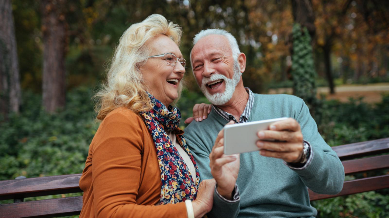 Senior couple using smart phone while sitting on a bench in the park
