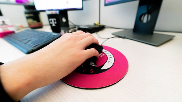 Employee uses computer mouse at branded workstation.