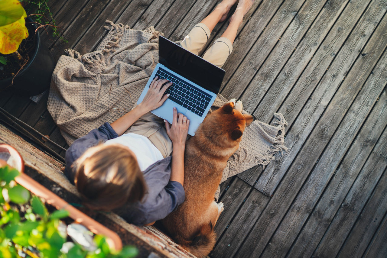 young woman working outdoors on home terrace sitting relaxed with dog