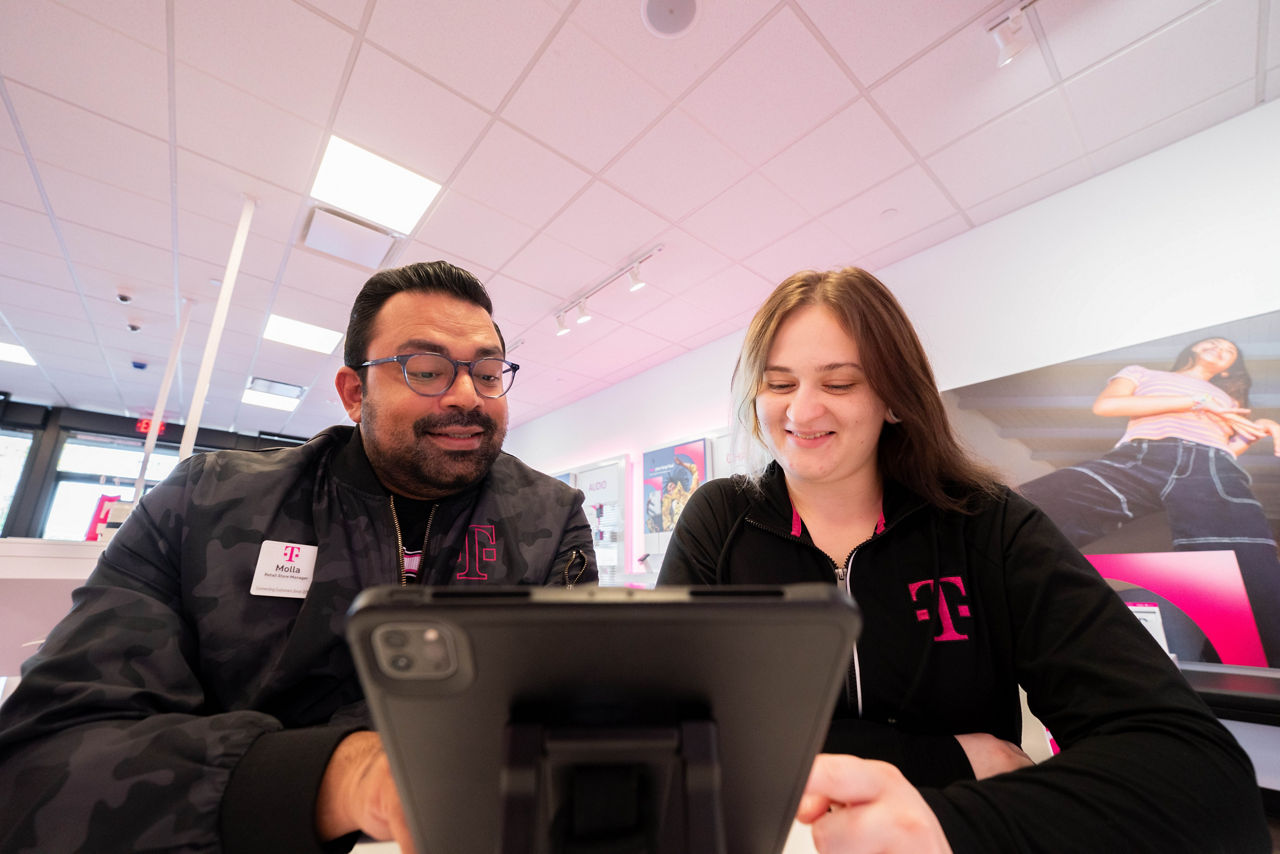 Three people in front of a wall with the T-Mobile logo.