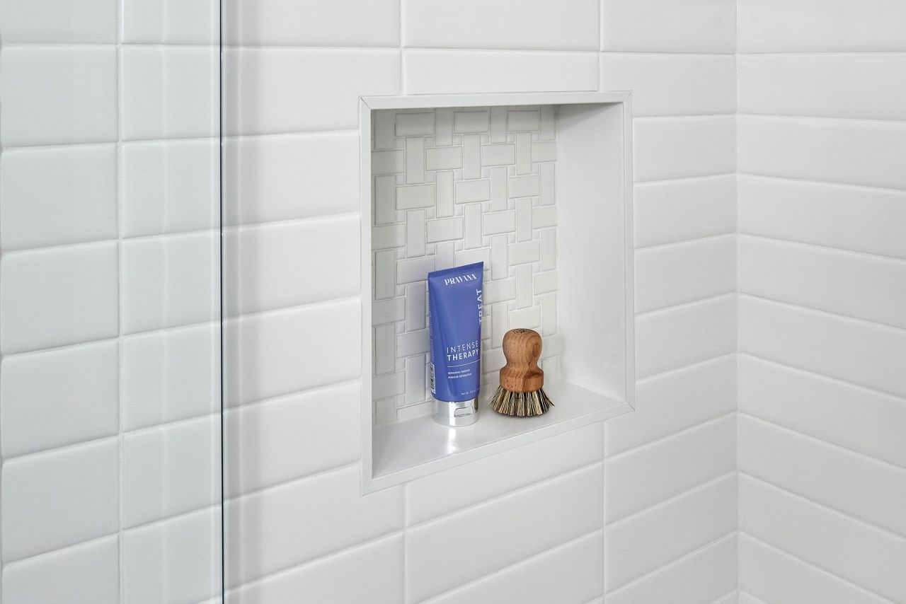 Shower with white horizontal-stacked subway tile and two small shower niches.