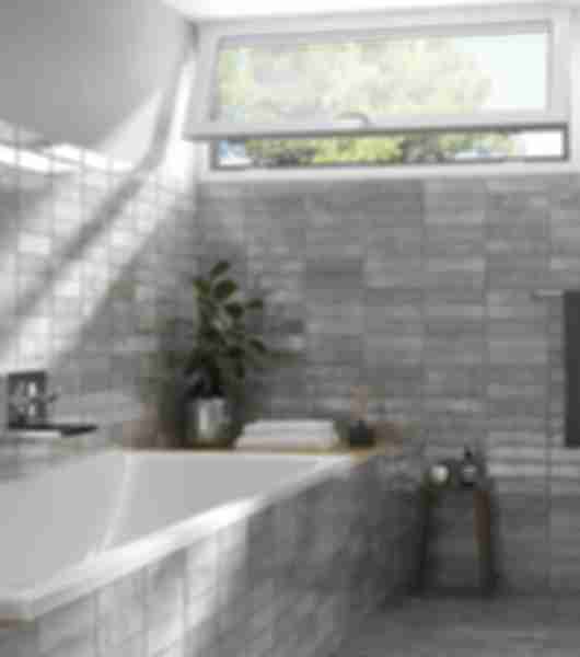 White bathtub with grey subway tile on surrounding bathroom walls and sides of tub.
