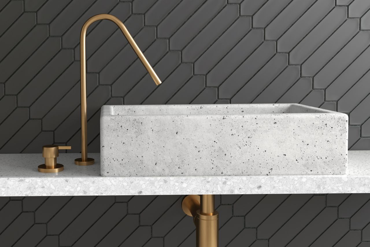 Black picket tile backsplash in a modern bathroom with gold fixtures and a marble sink basin.