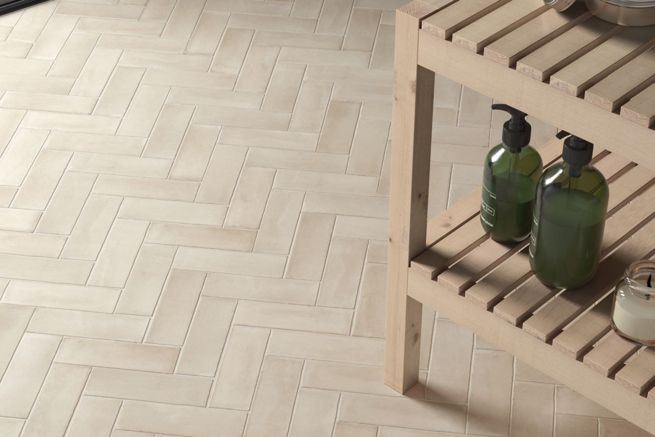 A beige handmade-look subway tile floor in herringbone pattern.