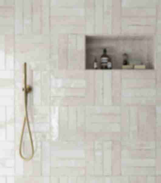 A shower wall with an alternating pattern of horizontal and vertical stacked subway tile.