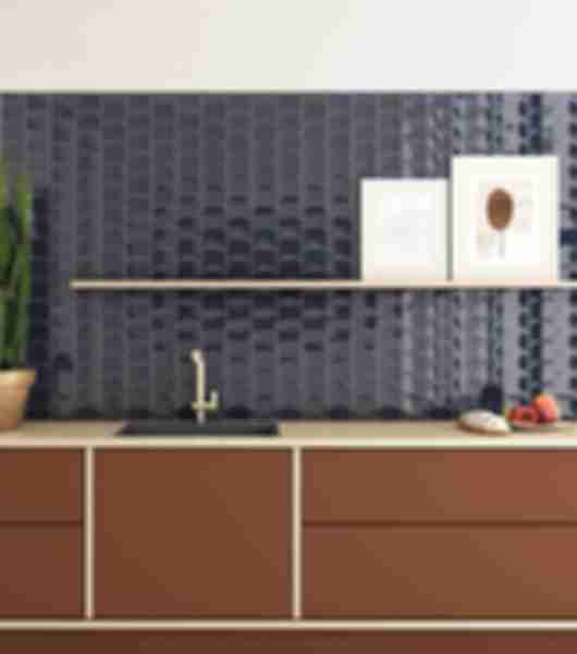 Wavy blue ceramic wall tiles behind a kitchen counter and brown cabinets.