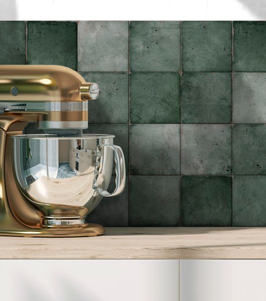In this kitchen, a backsplash of square green porcelain tile in varied shades of deep green creates a stunning focal point above a light beige counter and white lower cabinets.