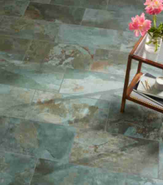 The floor of a living space is covered in large-format porcelain tile in layered shades of green that realistically mimic the appearance of natural slate.