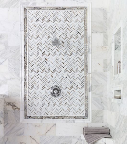 This elegant accent shower wall features chevron glass mosaic wall tile in a variety of white and gray tones that evoke the look of seashells.