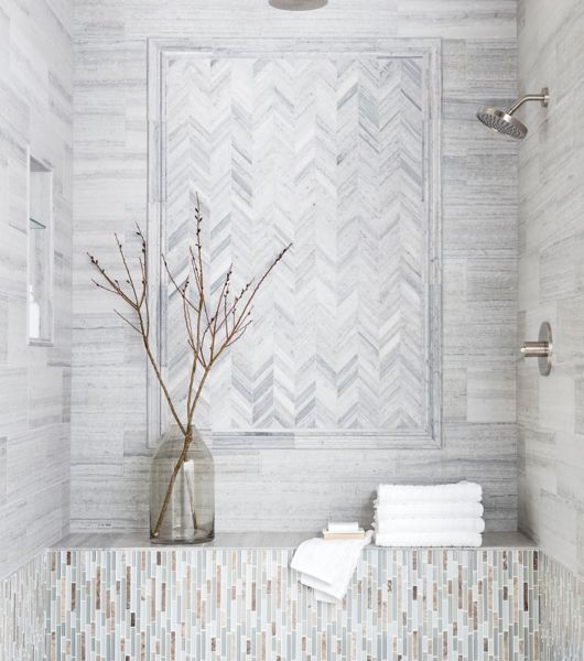 Sophisticated shower with grey limestone in chevron pattern with glass mosaic accents.